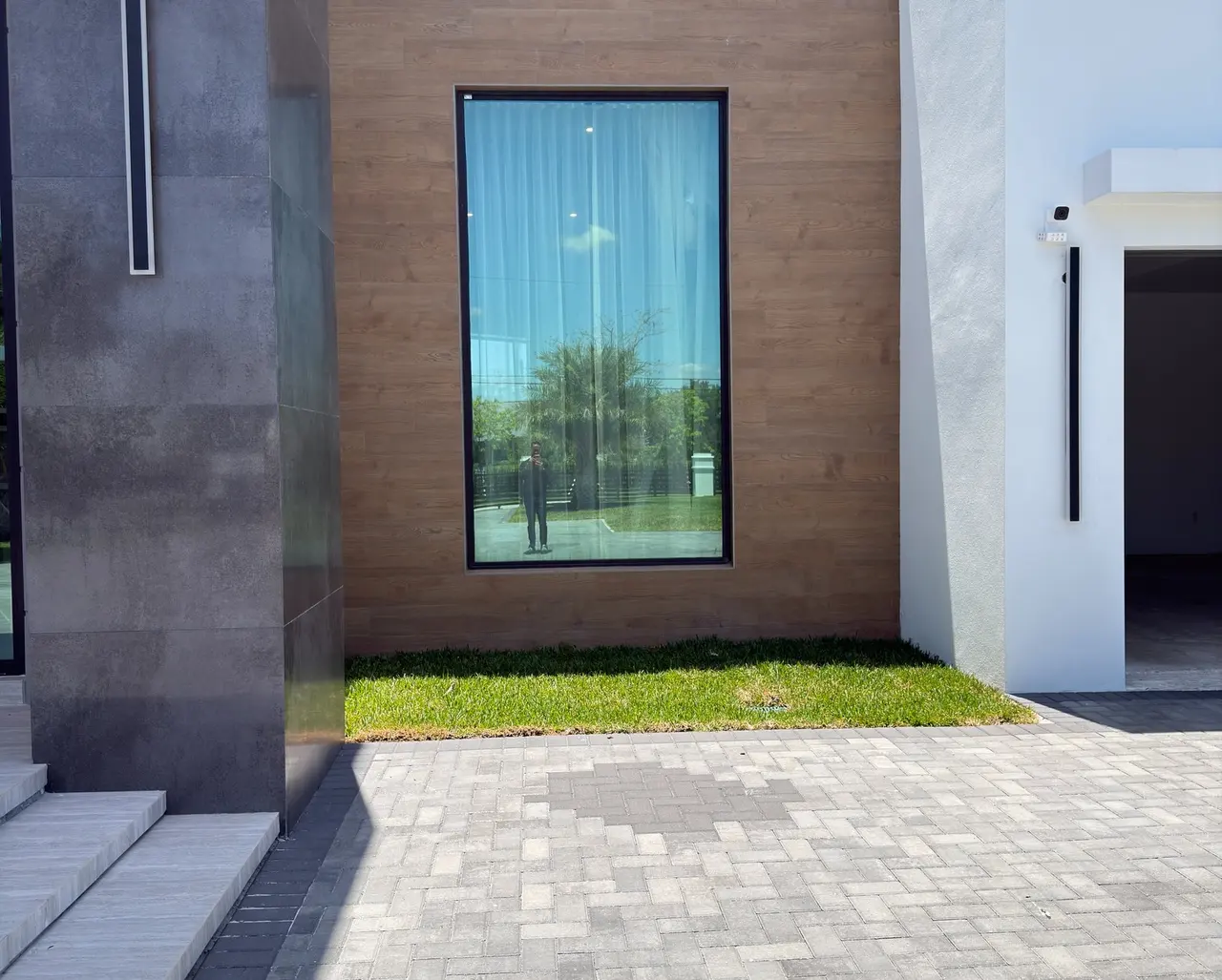 Flat grey stone entrance in daylight, with a strip of lawn and a paver path