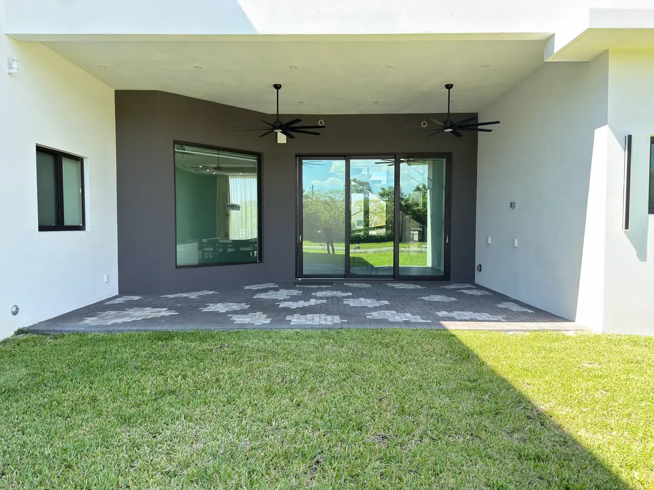 Empty covered patio with stained concrete, bare white walls and ceiling fans