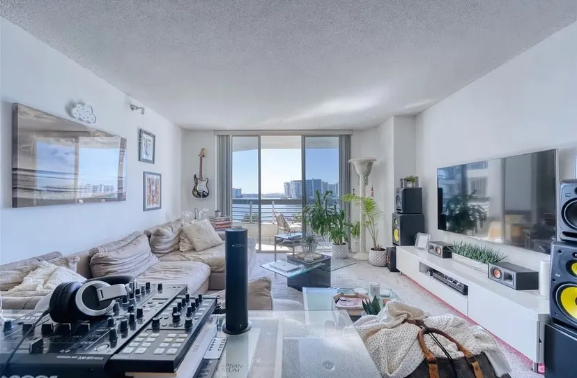 Cluttered living room with white walls, mismatched furniture and equipment on the floor
