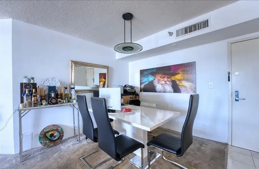 Dining corner with a glass table, black chairs and a console against a white wall