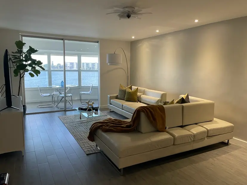 Sparse living room with beige walls, a low sofa and sliding doors onto the water